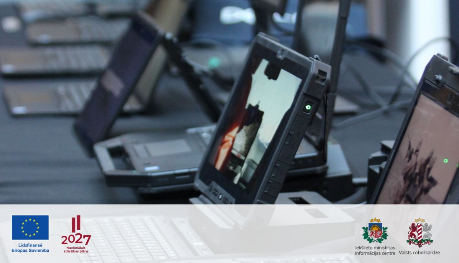 Operatīvo dienestu specializētā portatīvā tehniskā aprīkojuma un portatīvo datoru fotoattēls ar redzamiem Eiropas Savienības līdzfinansējuma, Latvijas Nacionālā attīstības plāna 2027.gadam, Iekšlietu ministrijas Informācijas centra un Valsts robežsardzes logotipiem.